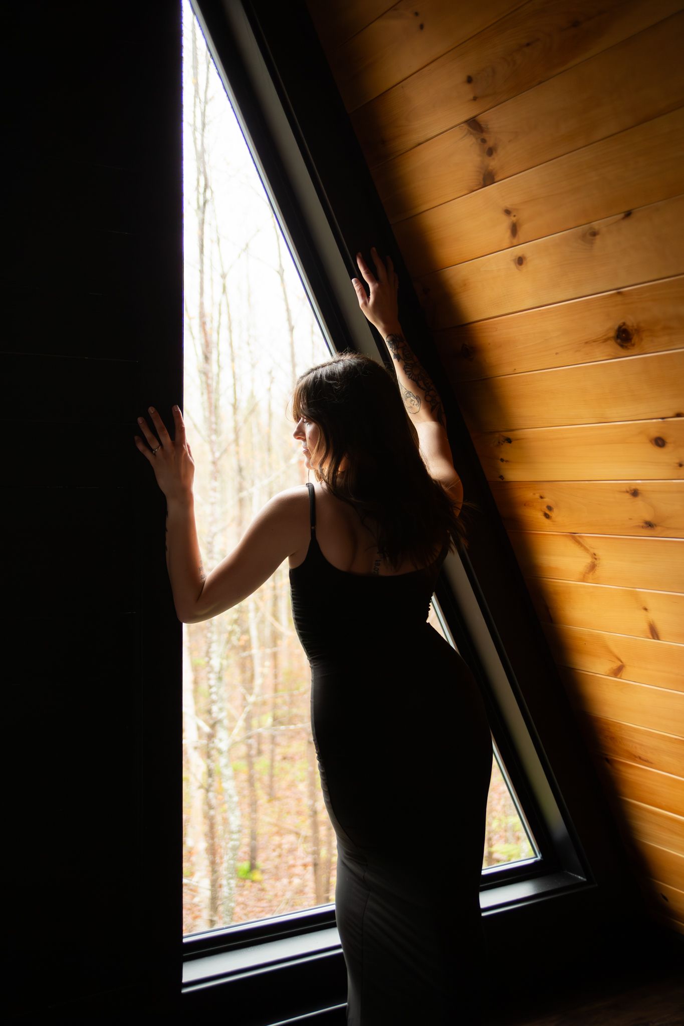 Silhouette against a wooden wall and window creates dramatic shadows in warm lighting.
