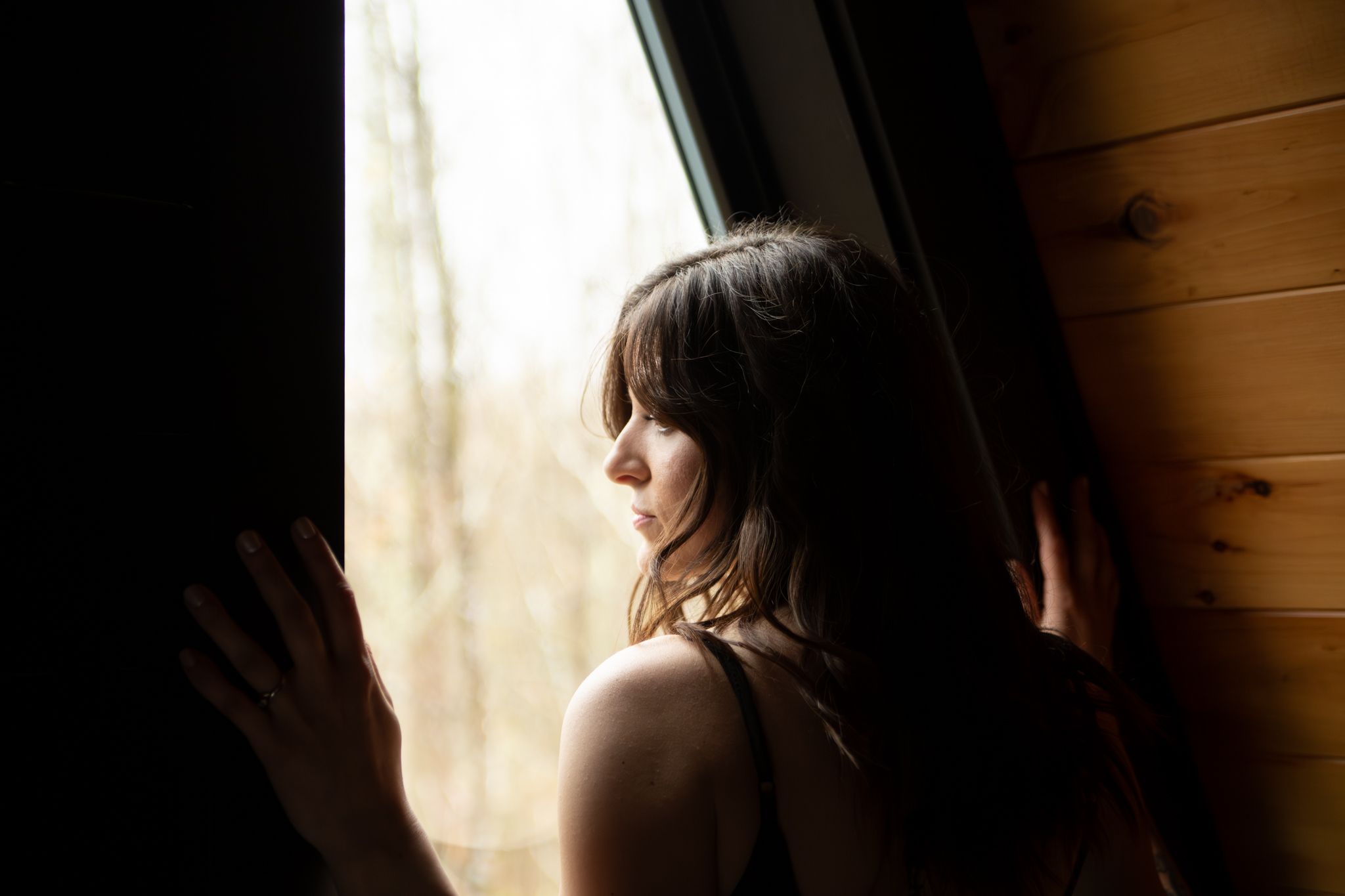 A silhouetted figure sits in contemplative pose by a window with natural light streaming in.