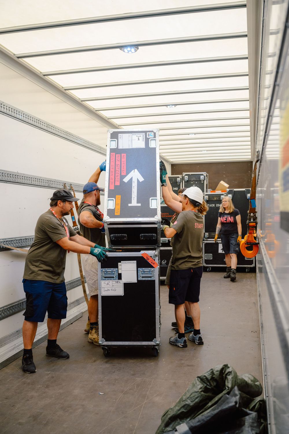 Crew members loading equipment and cases into a truck trailer.