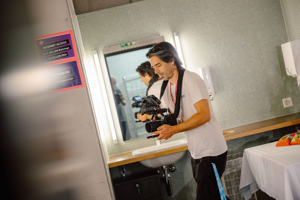 Person operating camera equipment in dimly lit room.