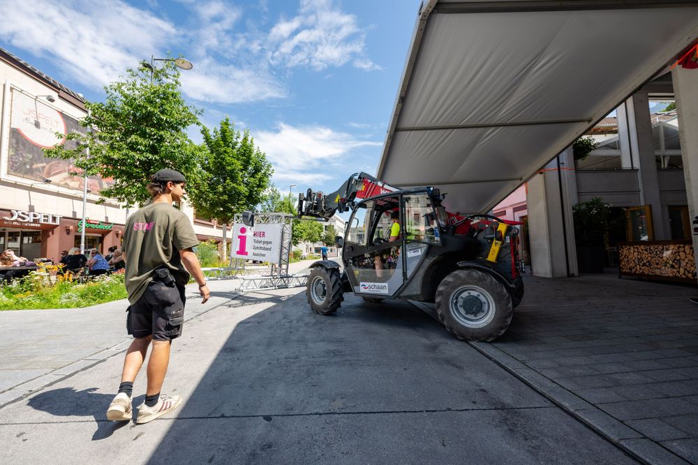 Utility vehicle parked under outdoor venue overhang on sunny day.