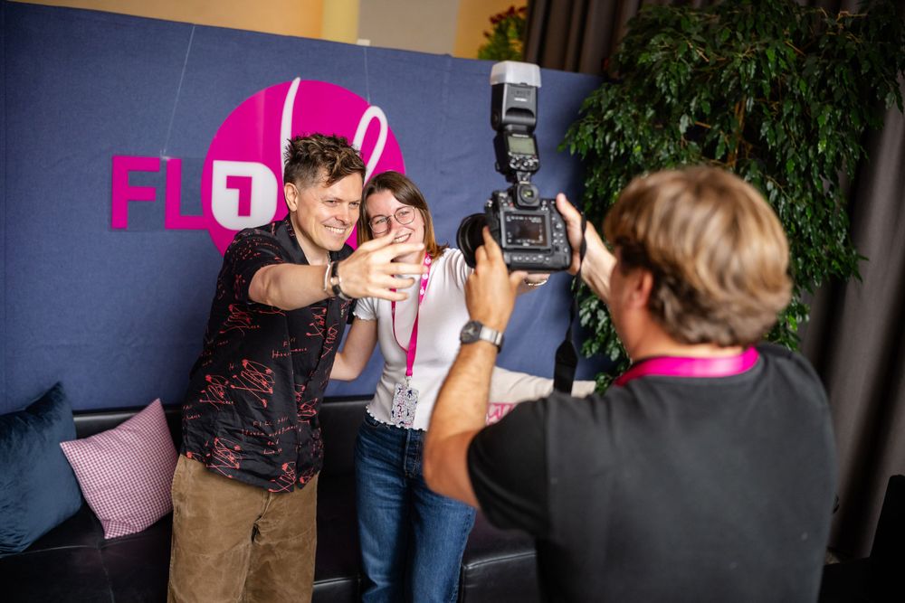 Photography session taking place against pink branded backdrop at event.