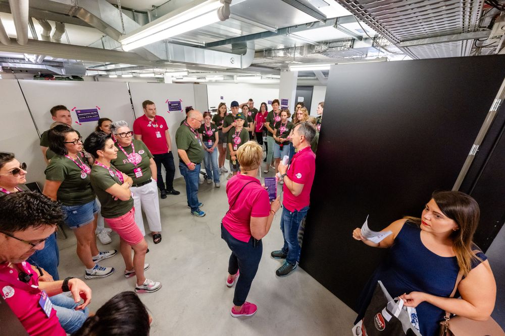 Large group gathered in basement or utility area for event instructions or briefing.