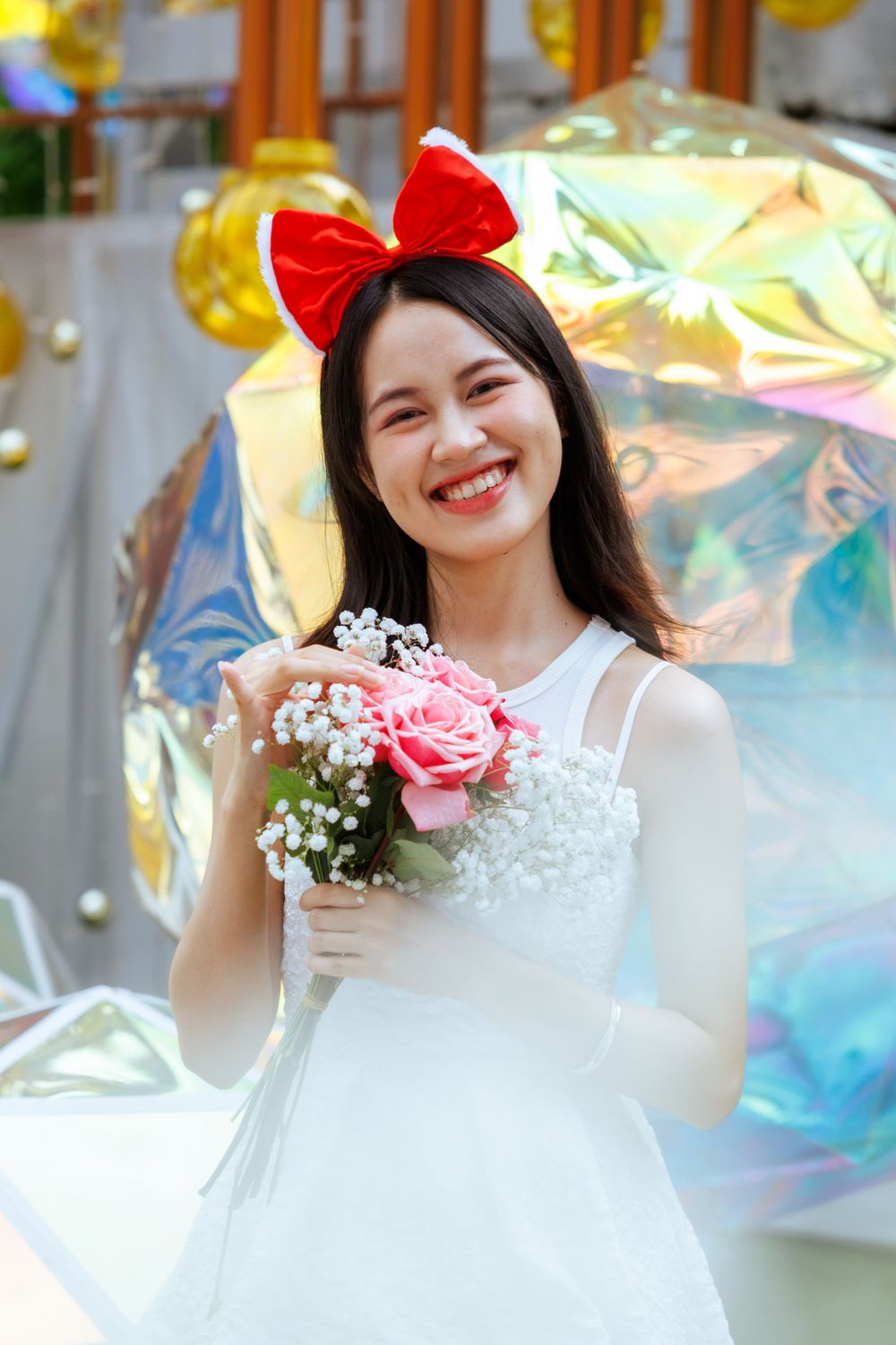 Pretty pose with pink roses and baby's breath flowers against shimmery background with red bow.