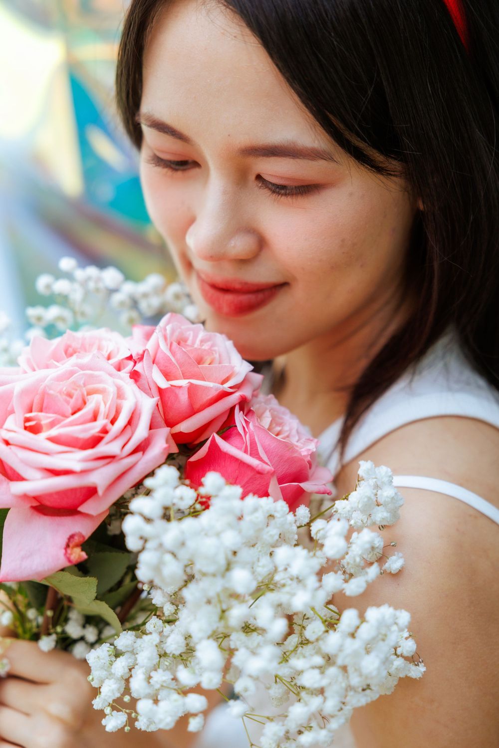 Close-up shot holding pink roses and baby's breath bouquet with gentle expression.