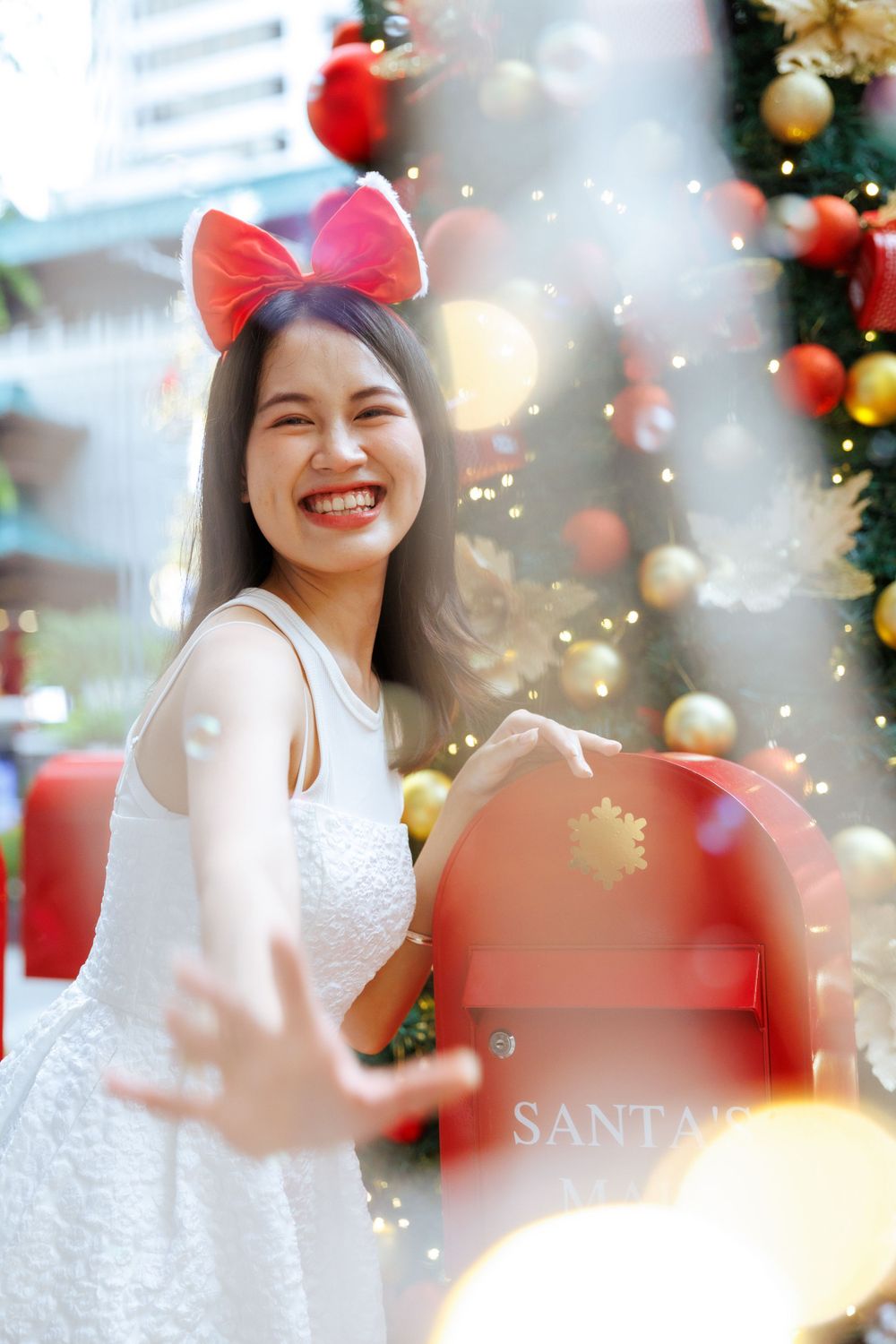 Joyful holiday portrait by Santa's mailbox with sparkling Christmas decorations.