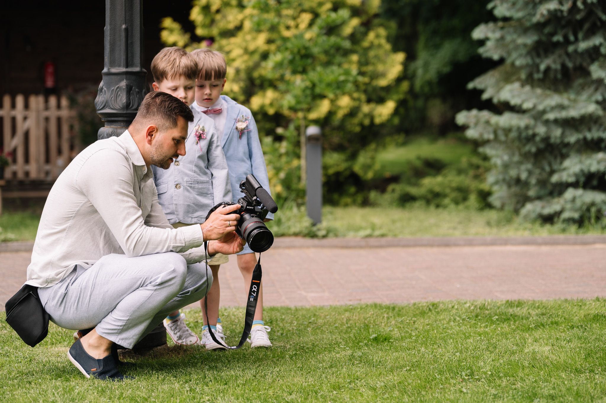 A photographer crouches with camera equipment while children watch with curiosity.