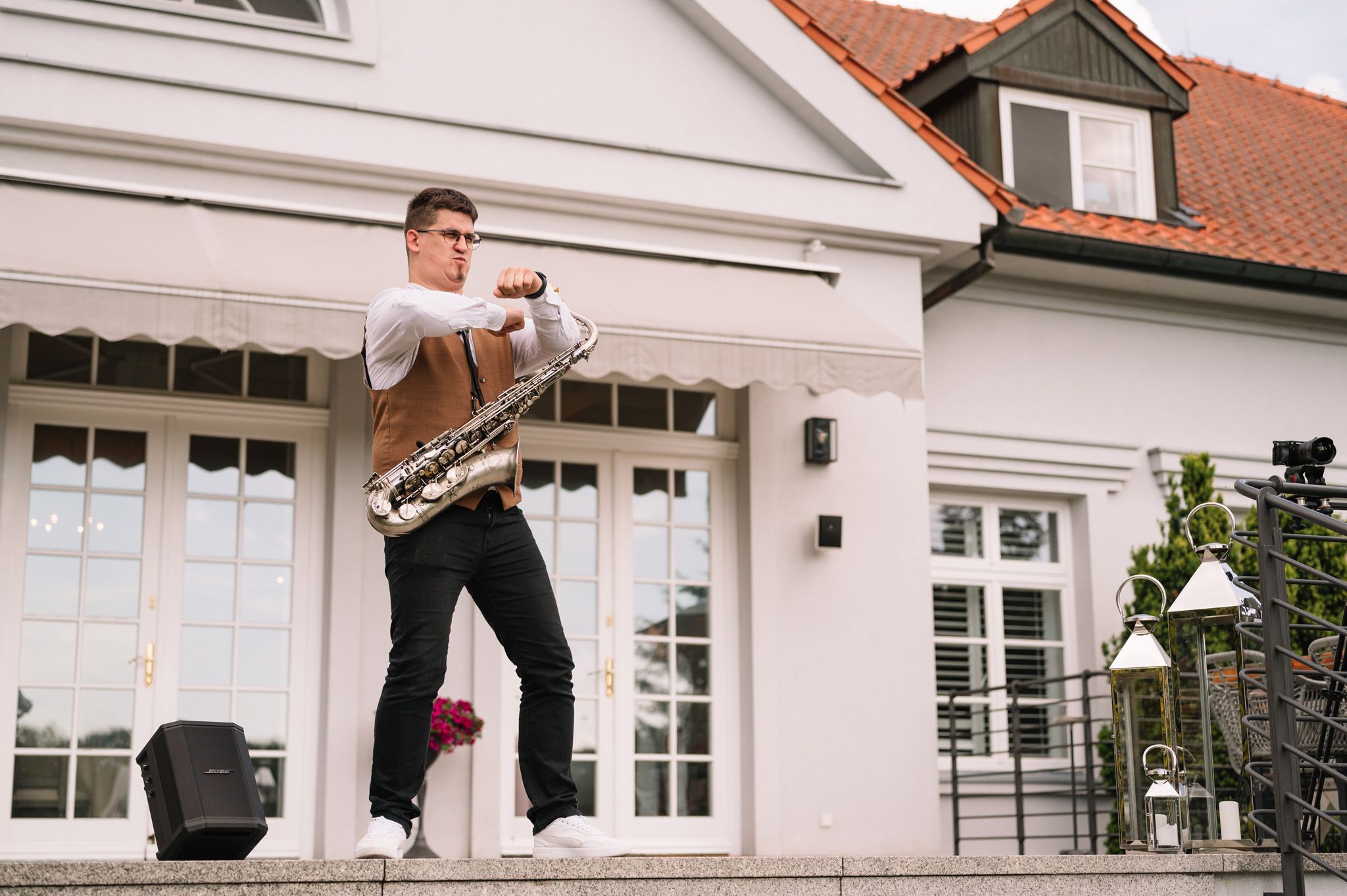 Person performs acrobatic pose on white porch steps of a classic house.