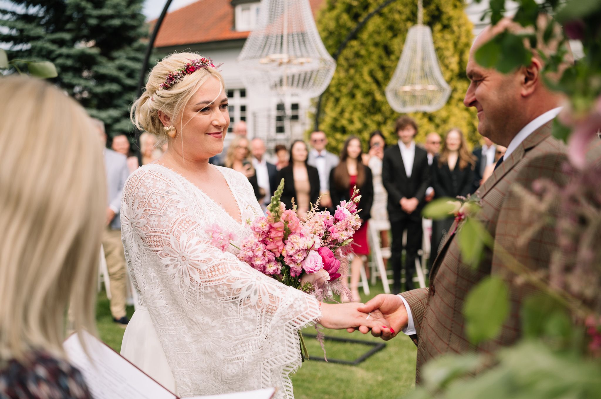 Outdoor wedding ceremony with couple exchanging vows under white gazebo.