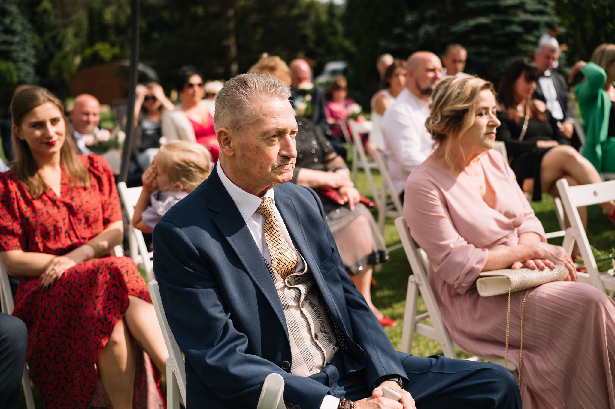 Wedding guests seated outdoors at a summer ceremony.