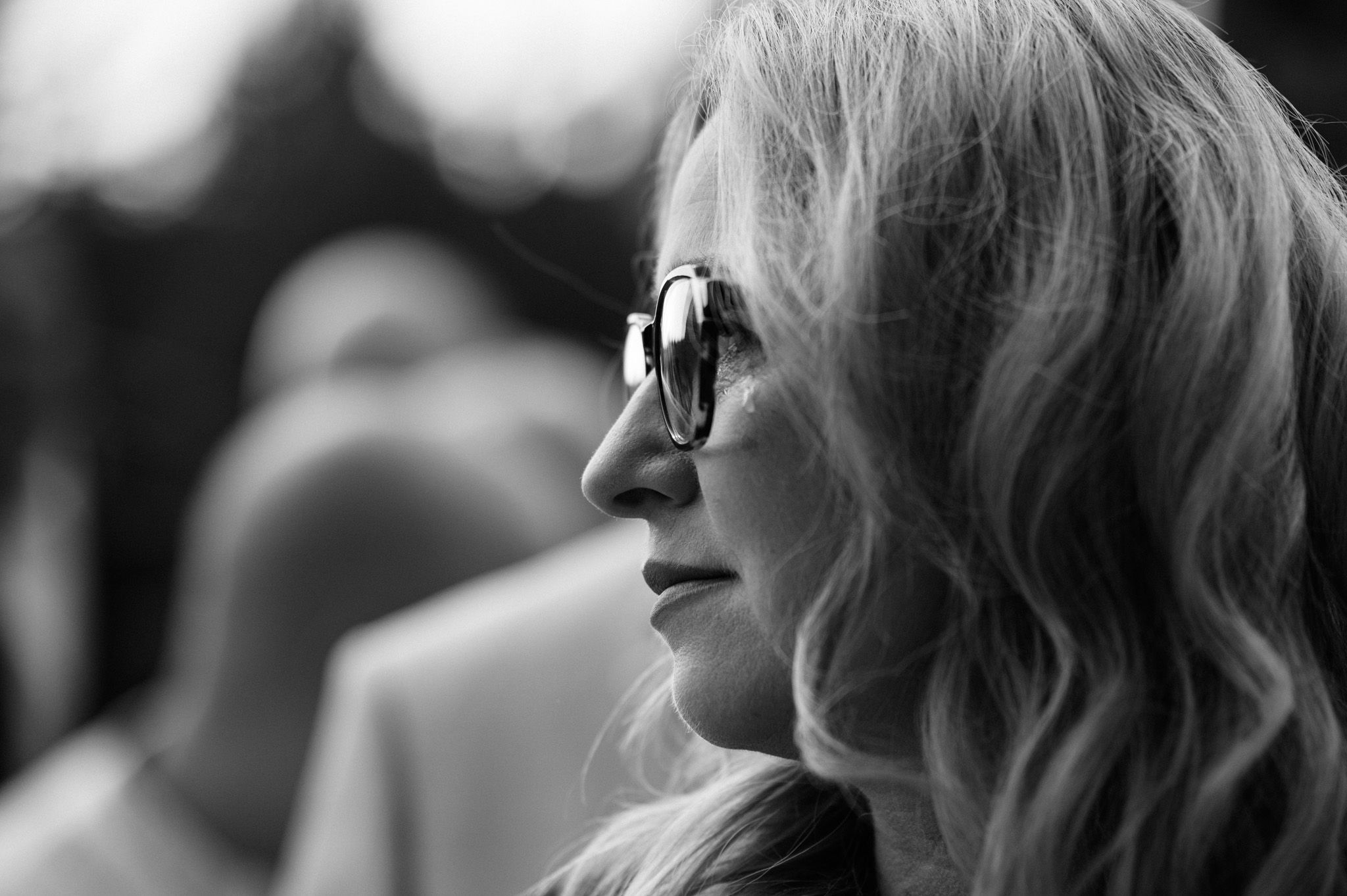 Black and white profile portrait of someone wearing sunglasses at an outdoor event.