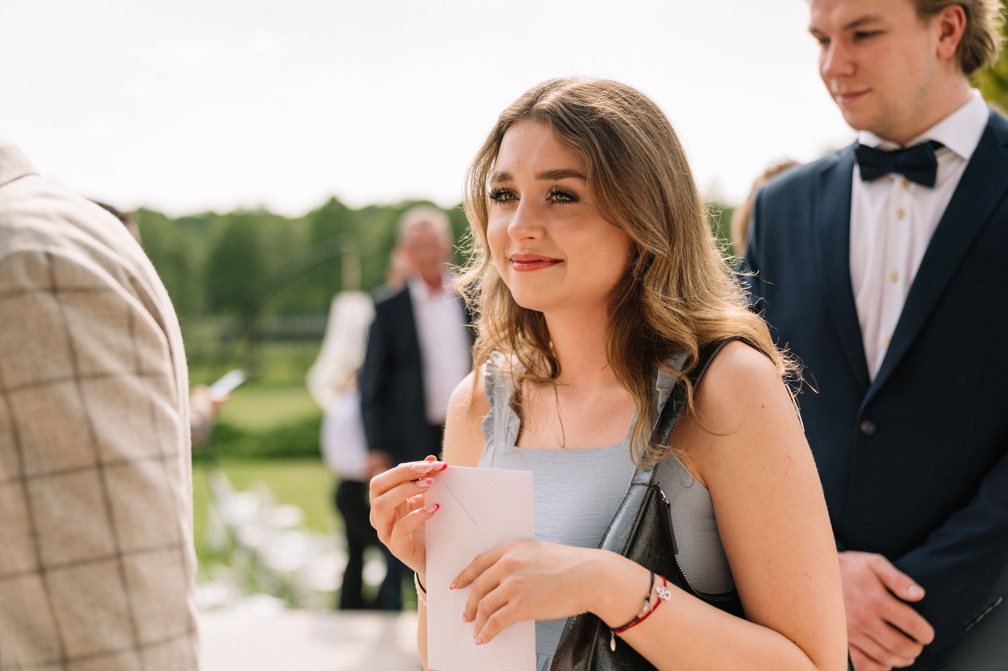 Guests mingle and converse during an elegant outdoor wedding reception on a sunny day.