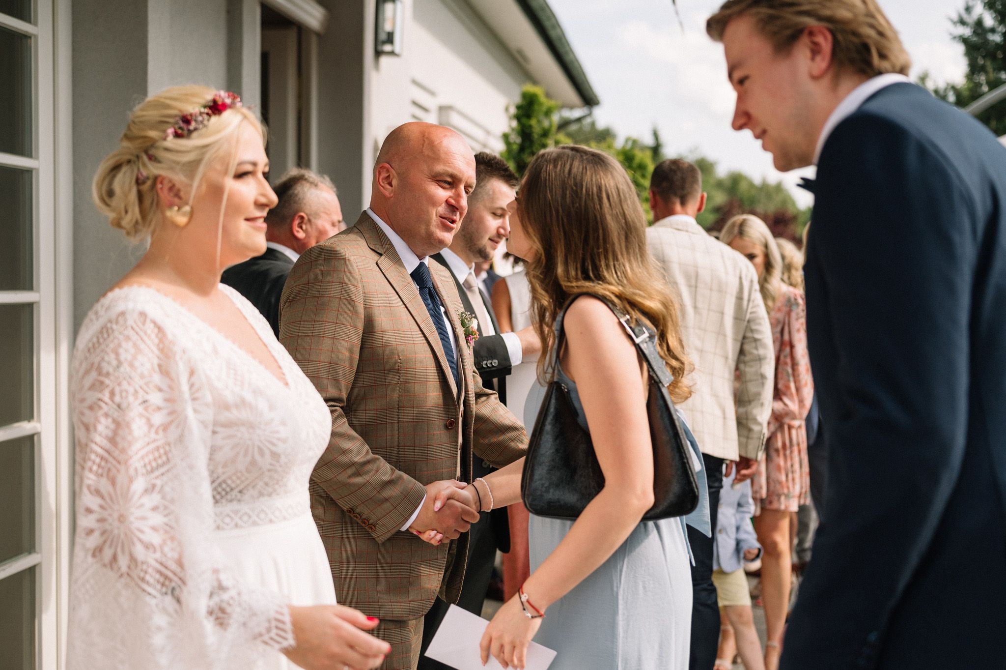 Wedding guests gather for conversations during an outdoor reception with beautiful white decor.