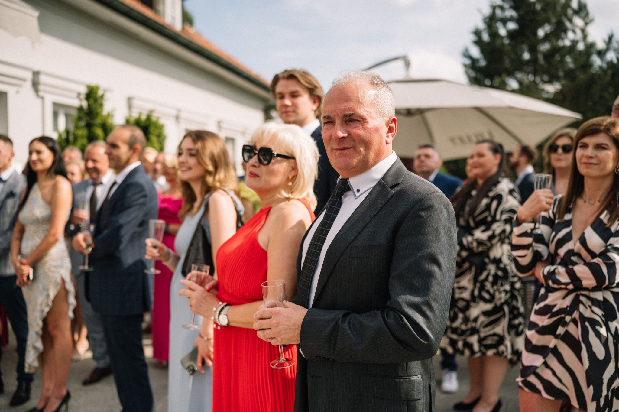 Wedding guests socialize at an outdoor reception with elegant formal attire.