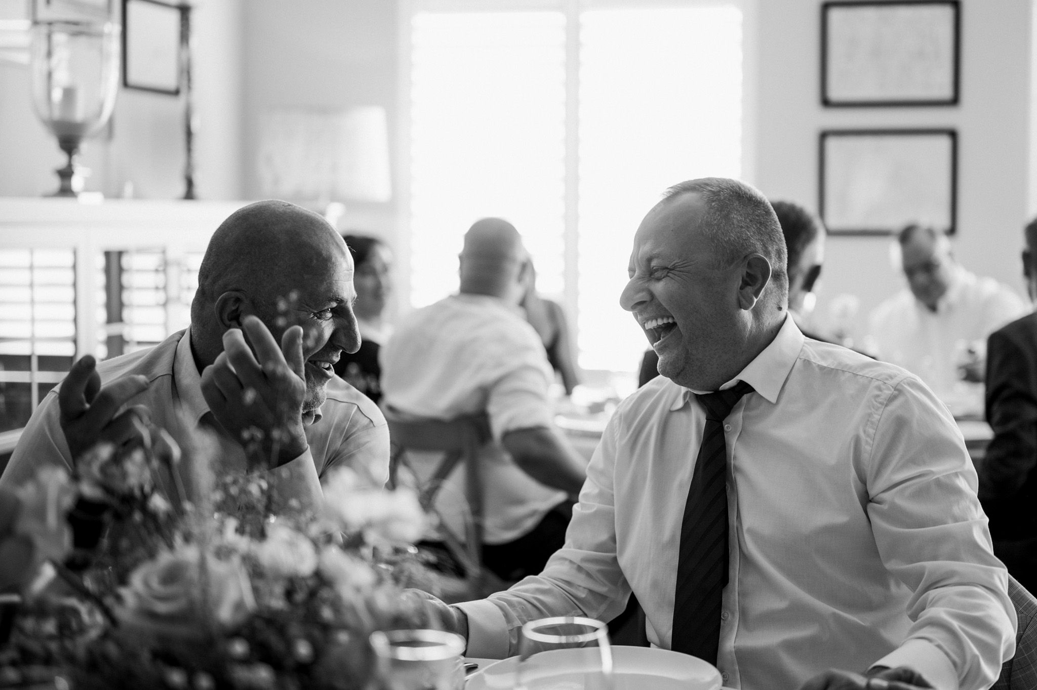 Black and white candid photo of guests enjoying conversation at an elegant event.
