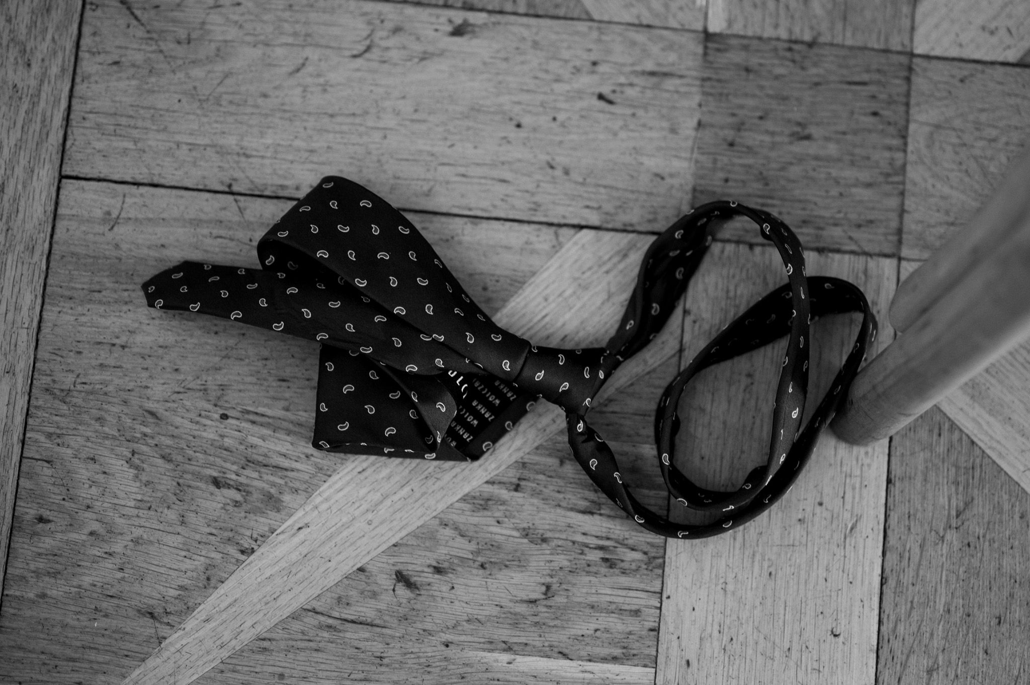 A black polka dot bow tie and suspenders lying on a wooden floor.