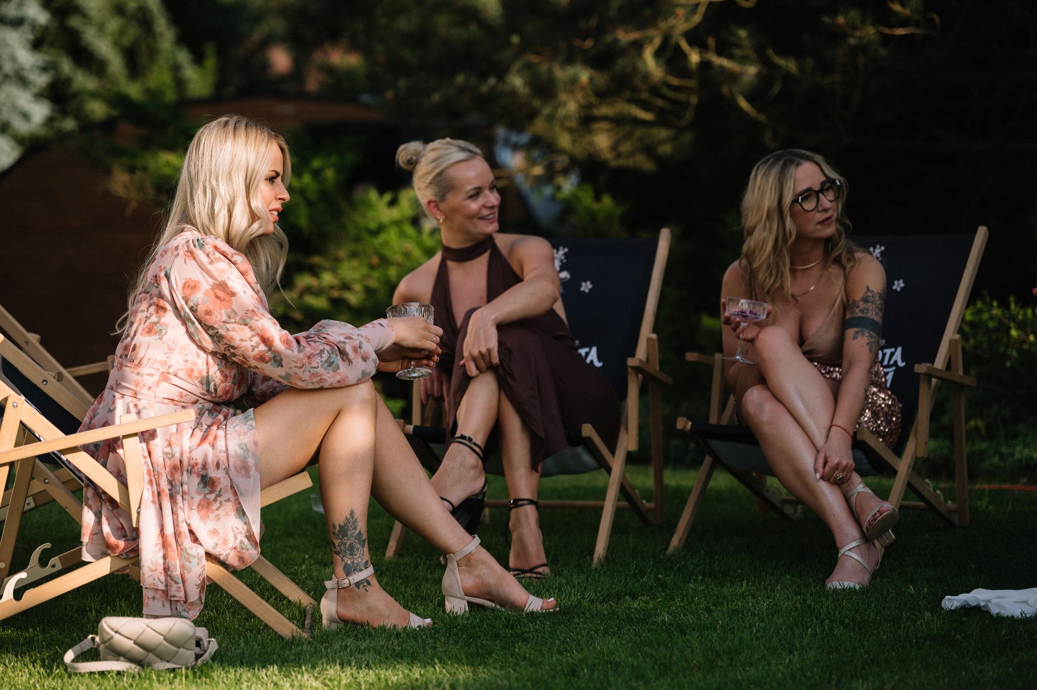 Three people relaxing in lawn chairs during an outdoor summer gathering.