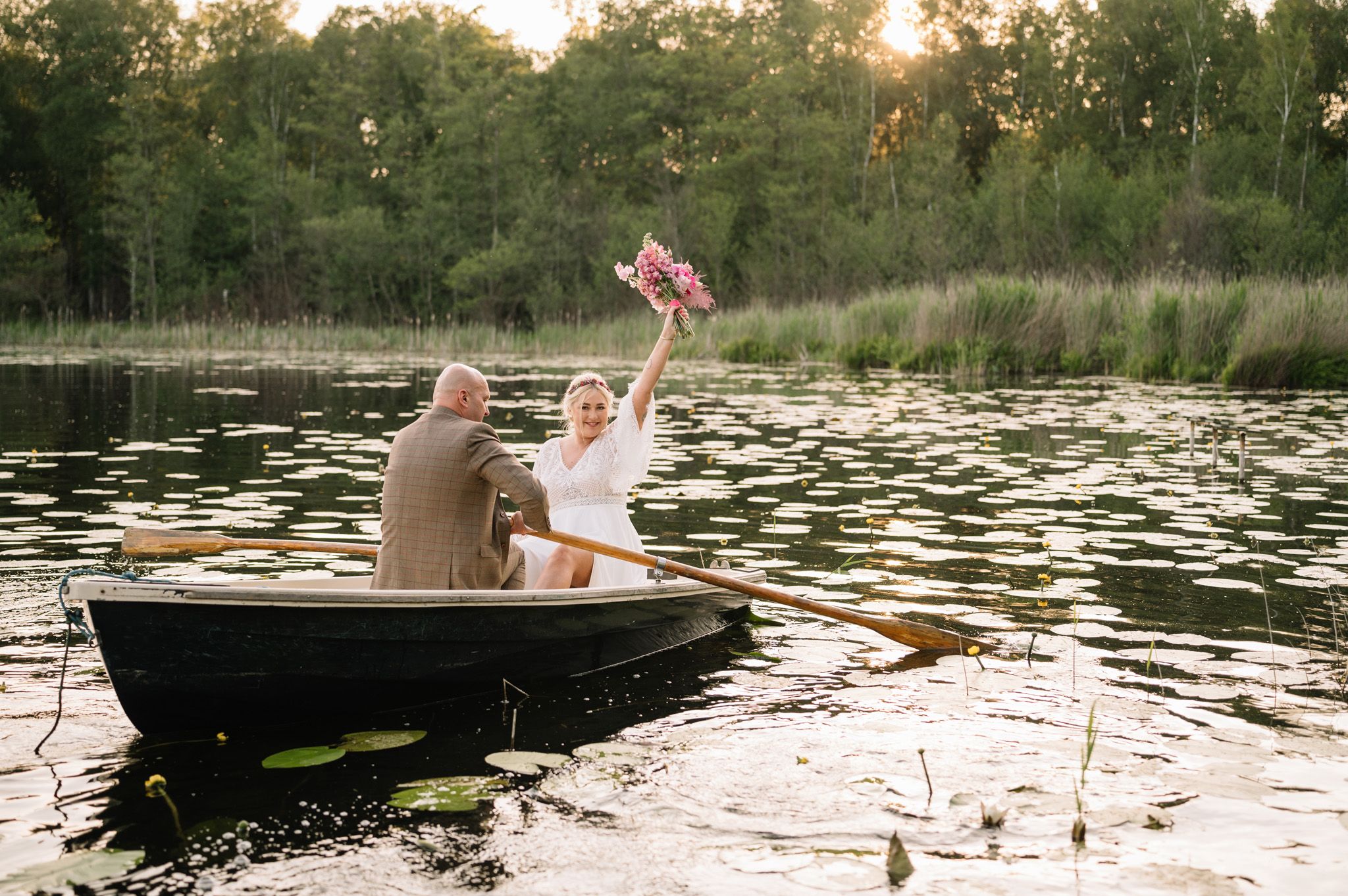 Romantic boat ride on lily pad covered lake during golden hour.