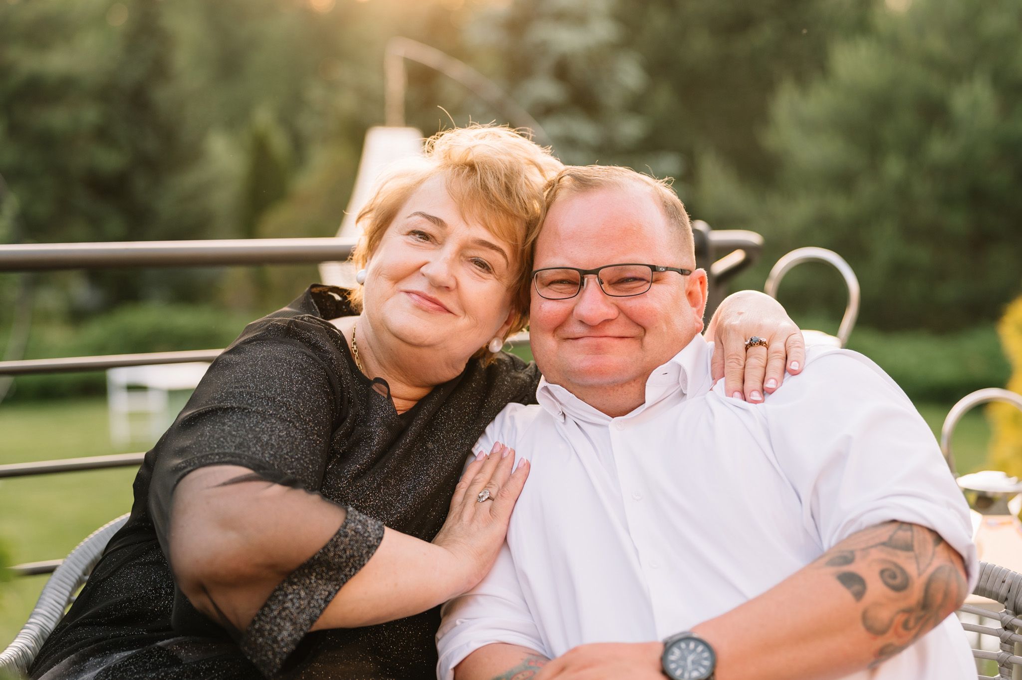 A relaxed couple sits together outdoors on a summer evening.
