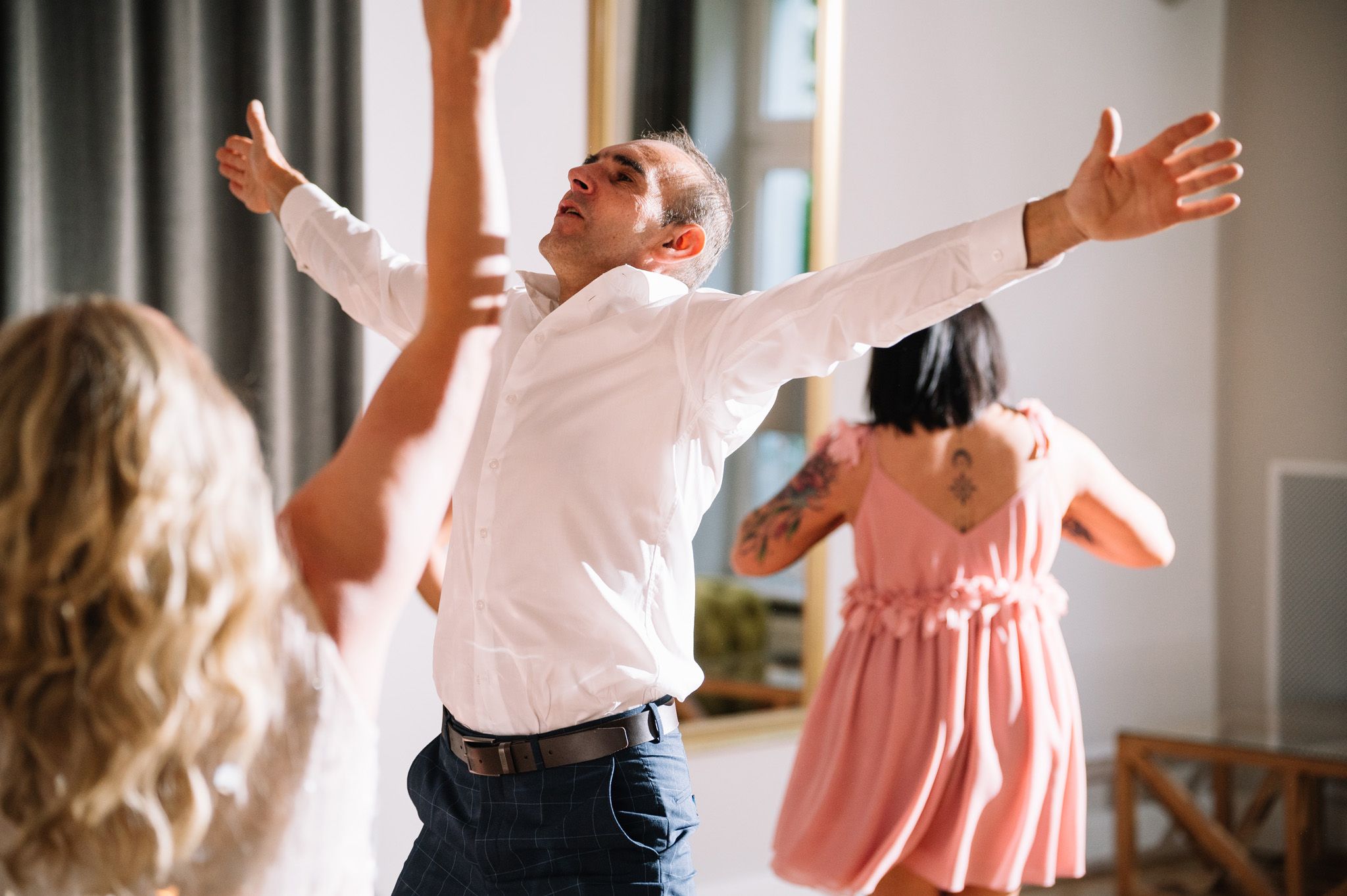 Wedding guests dancing and celebrating with their arms raised in joy.