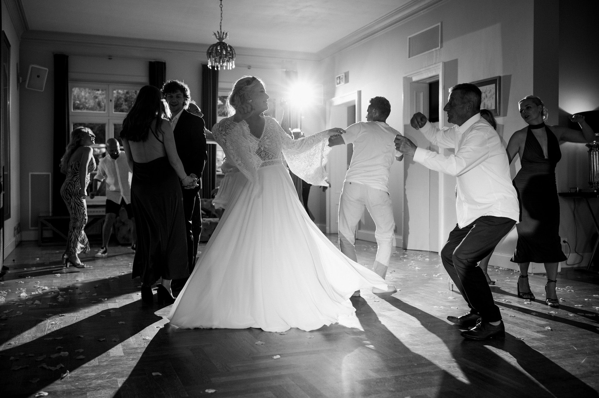 A black and white shot of wedding guests dancing at a reception.