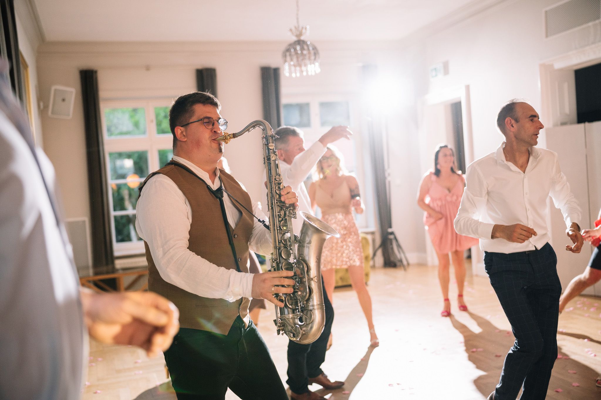 Musicians perform at a wedding reception while guests dance.
