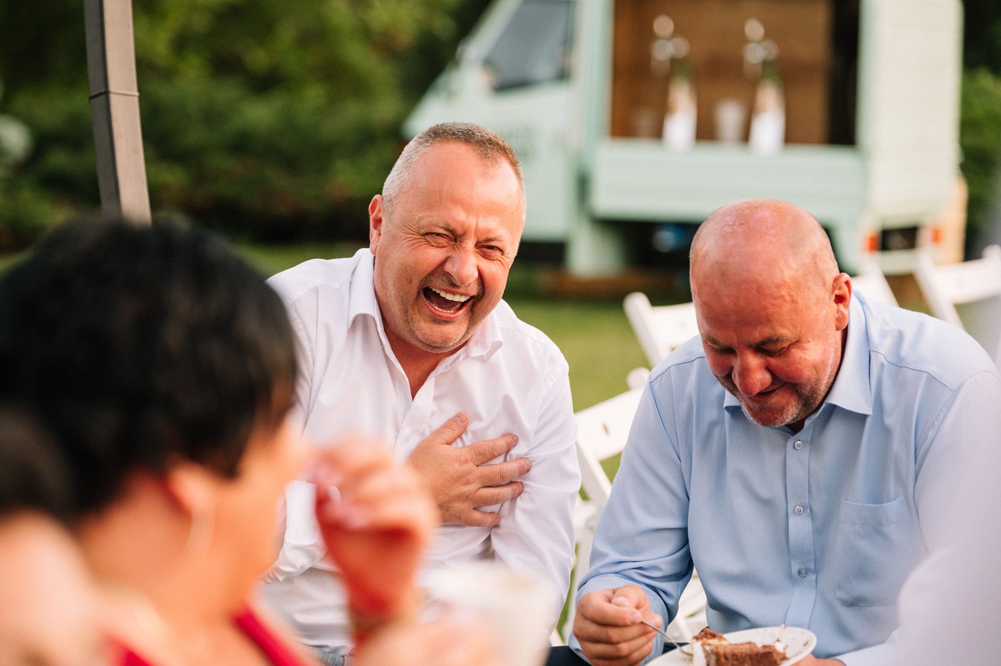 Two guests share a joyful moment while dining at an outdoor event.