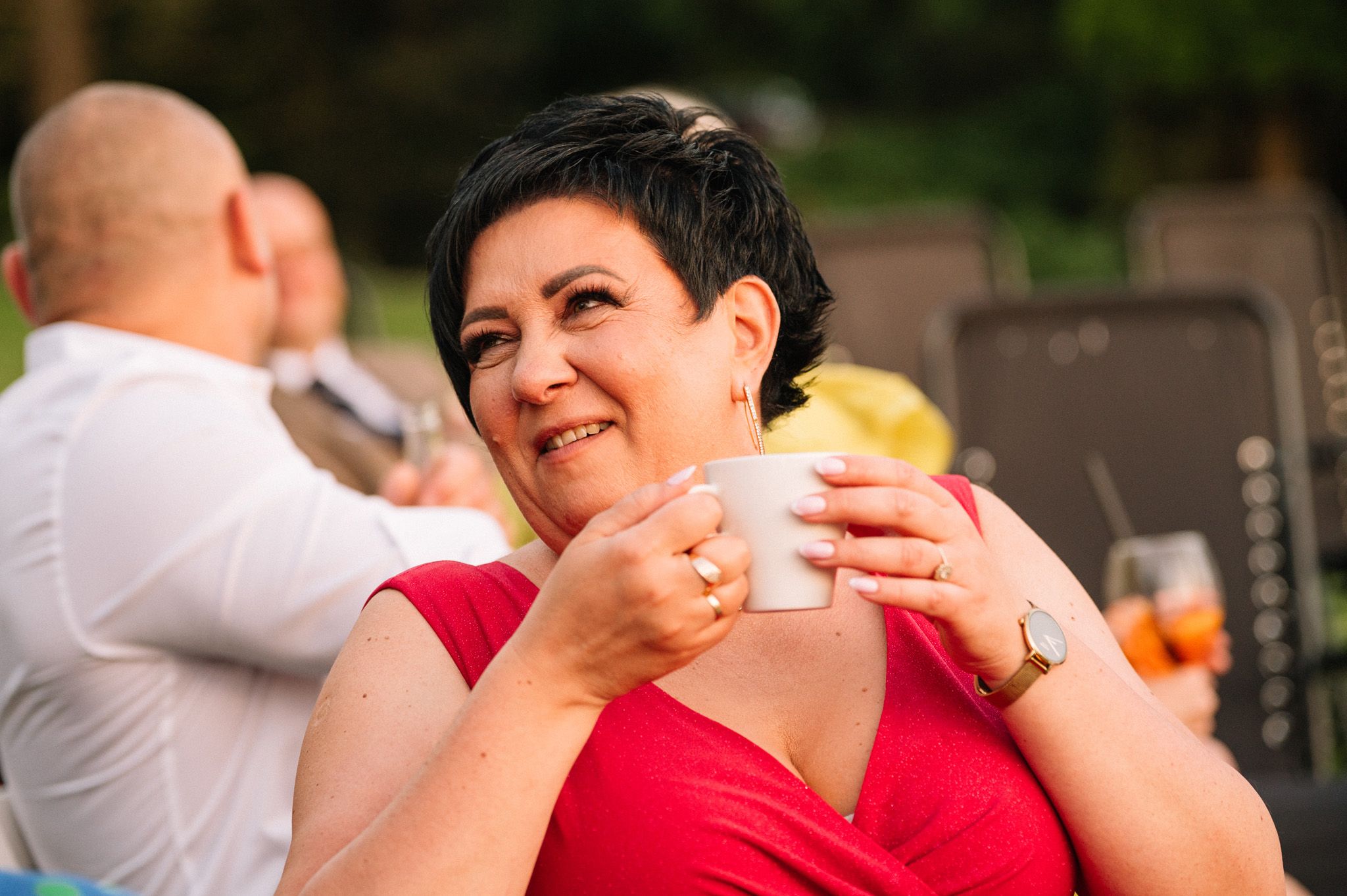 Guest in red dress enjoying drinks during outdoor celebration.
