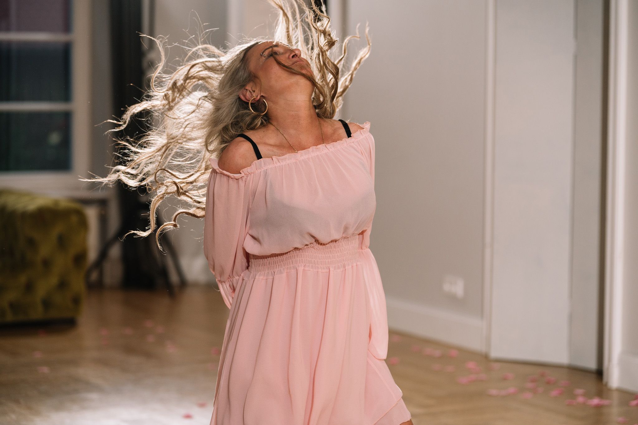 Woman in pink dress twirling and dancing with flowing hair in indoor venue.