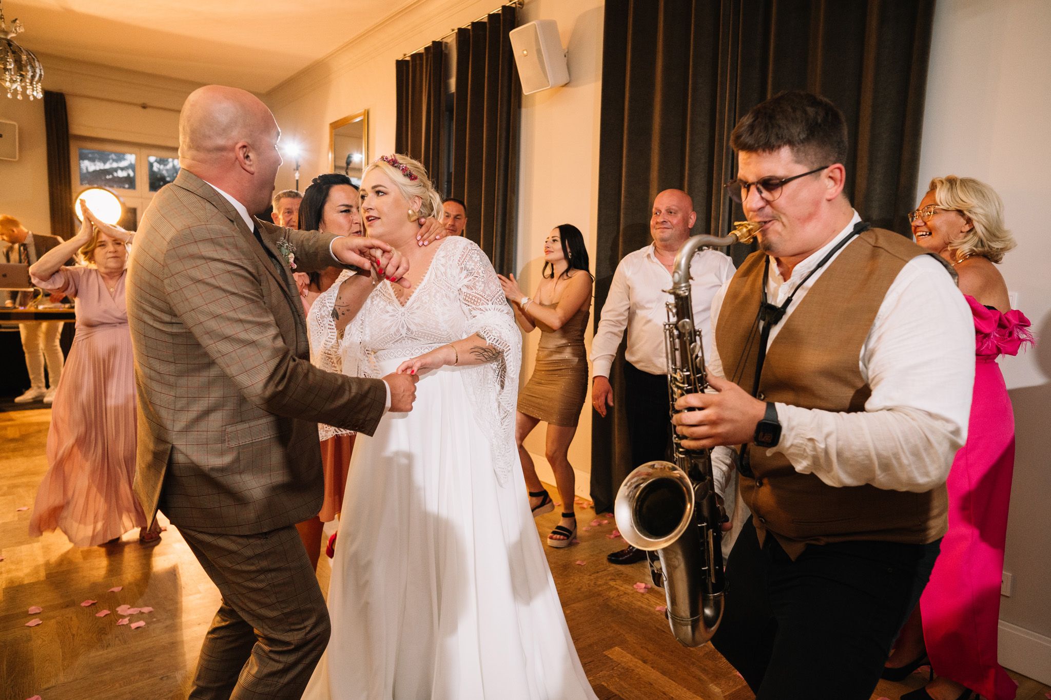 Dancers enjoying reception with saxophone player performing in brown vest.