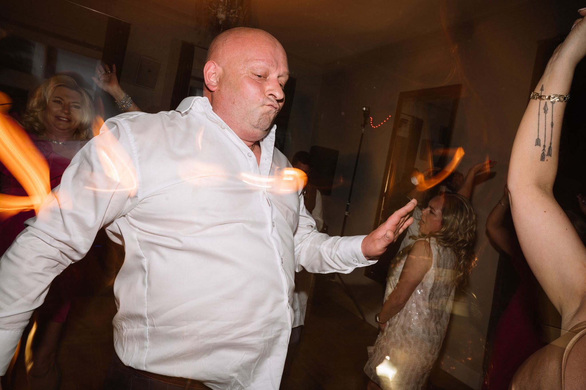 Party guest in white shirt dances energetically at wedding reception with motion blur effects.