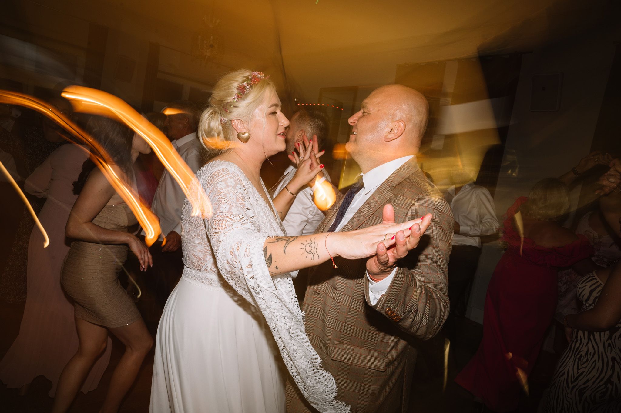 Dancing couple at wedding reception with orange light trails creating dynamic motion effect.