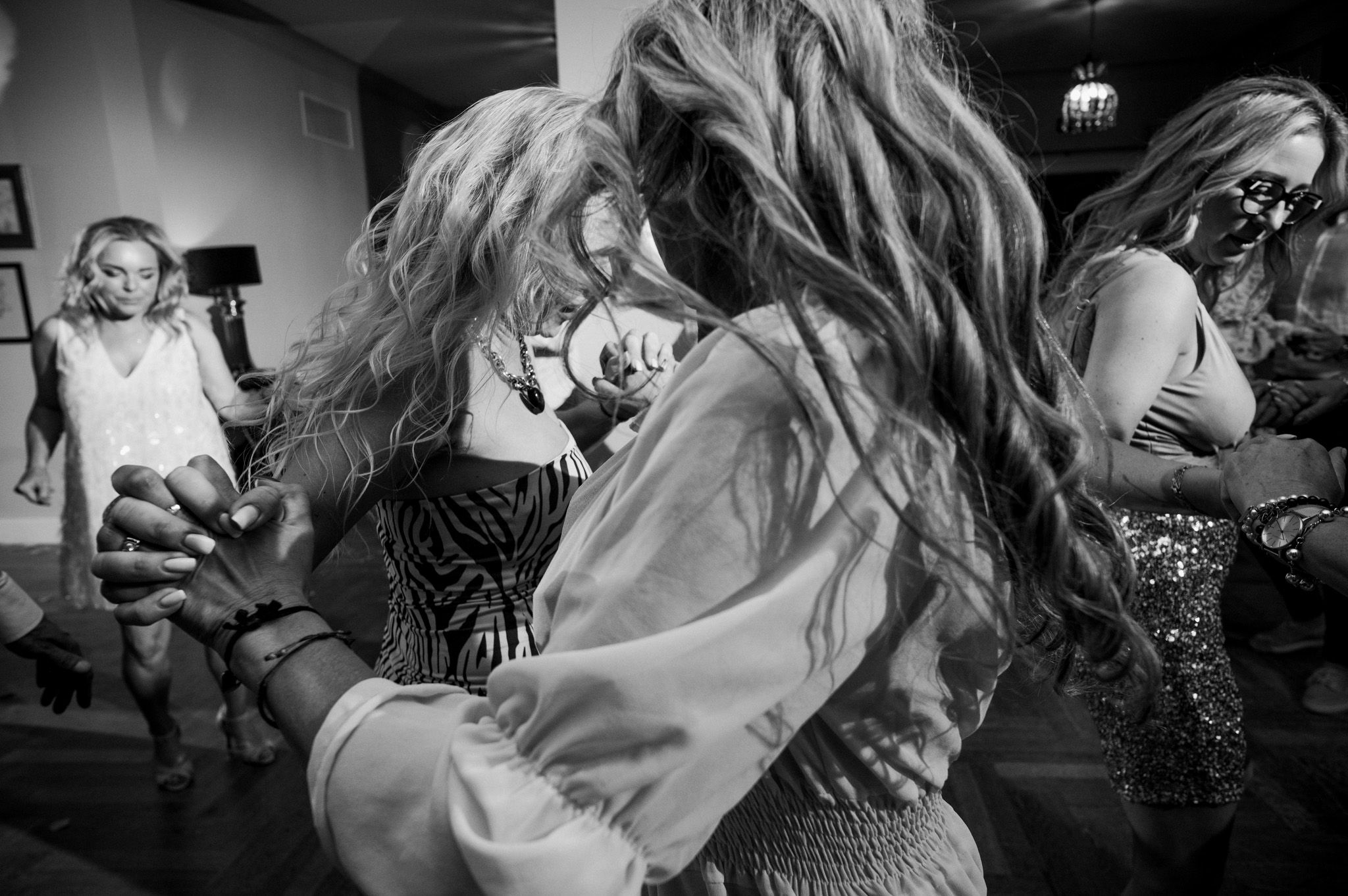 Black and white photo captures energetic dancing and movement at a celebration.