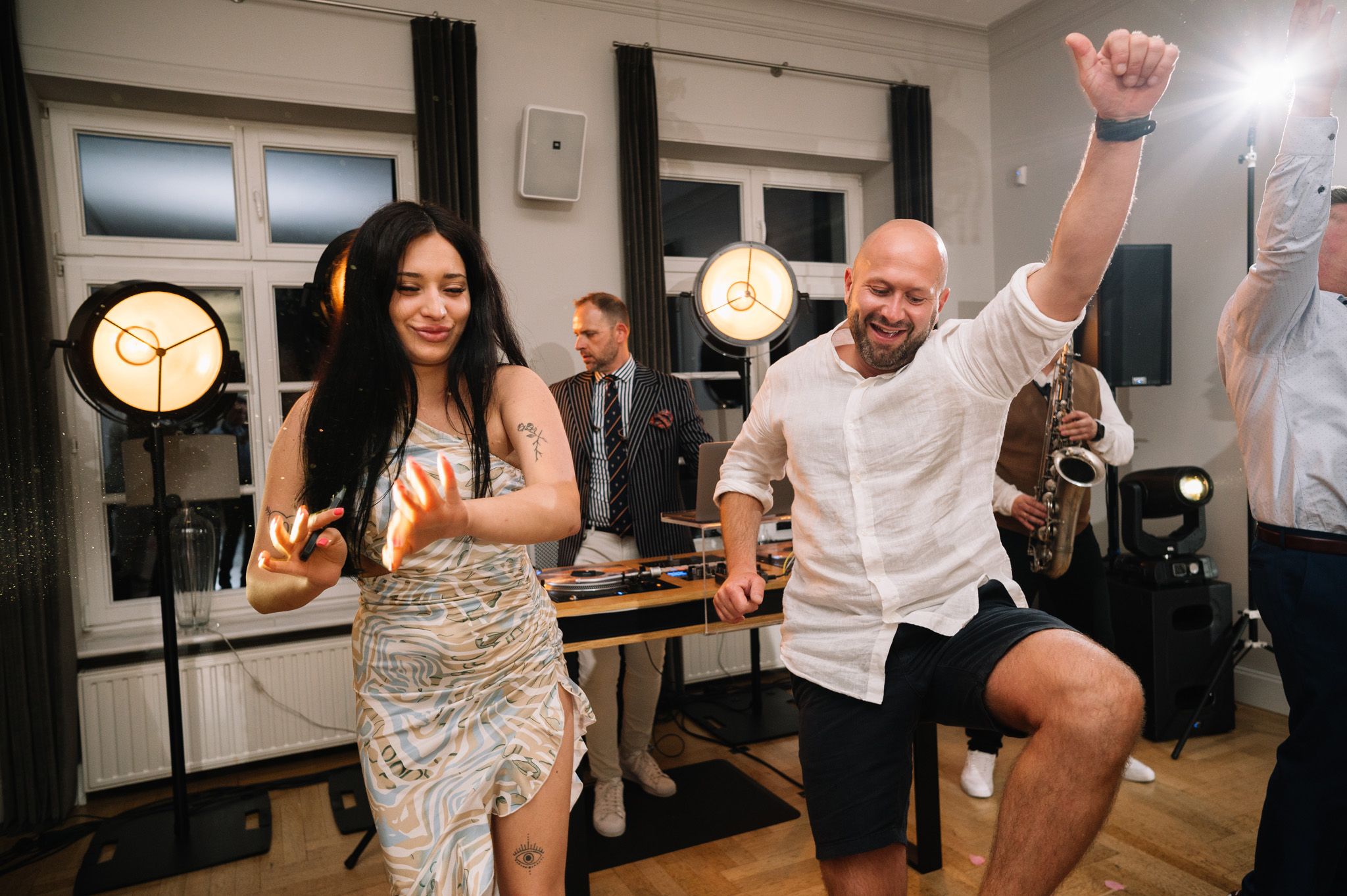 Energetic dancing and celebration at a party with DJ equipment visible in background.