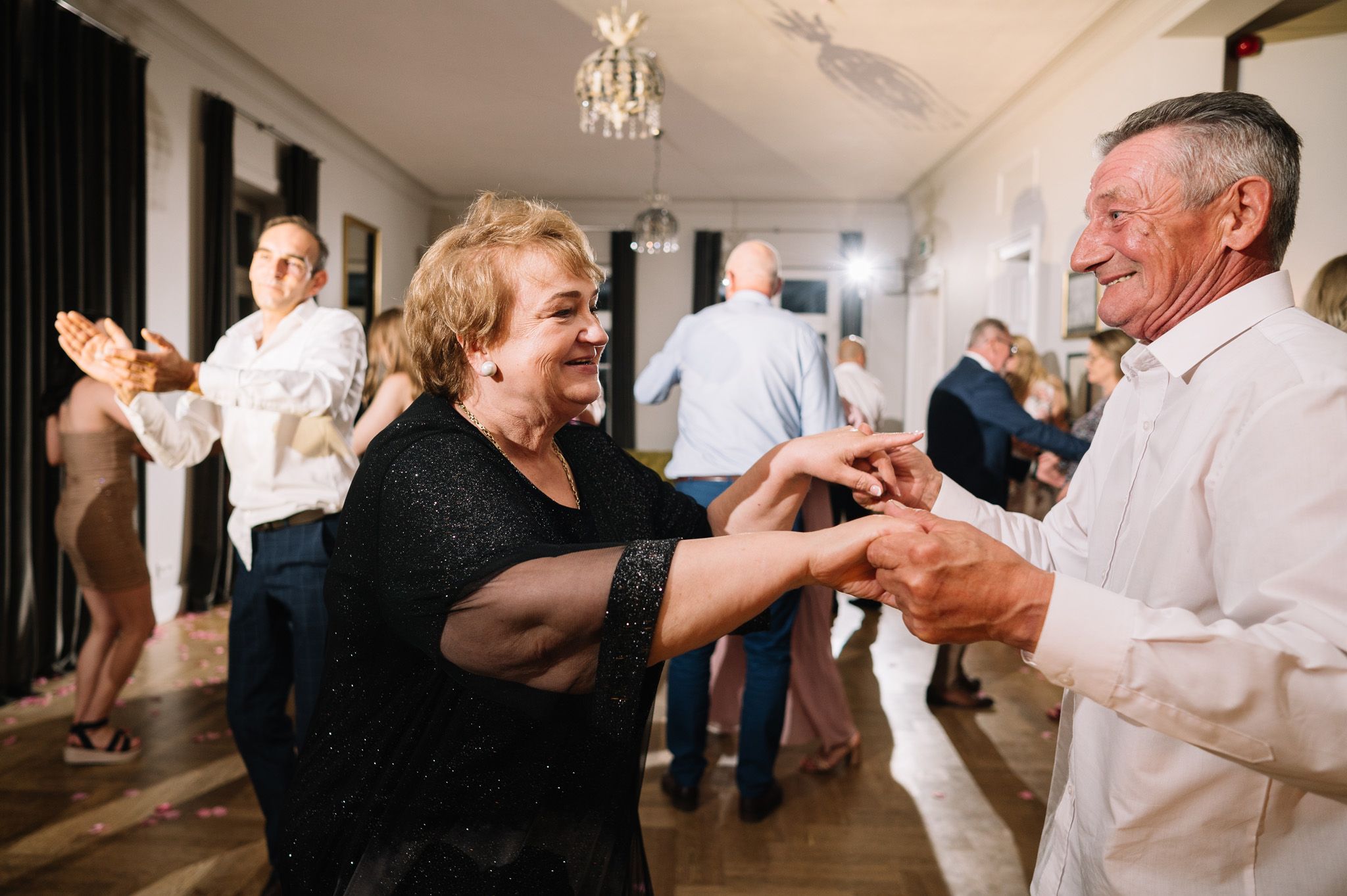 Joyful couples dance together during a lively indoor celebration event.