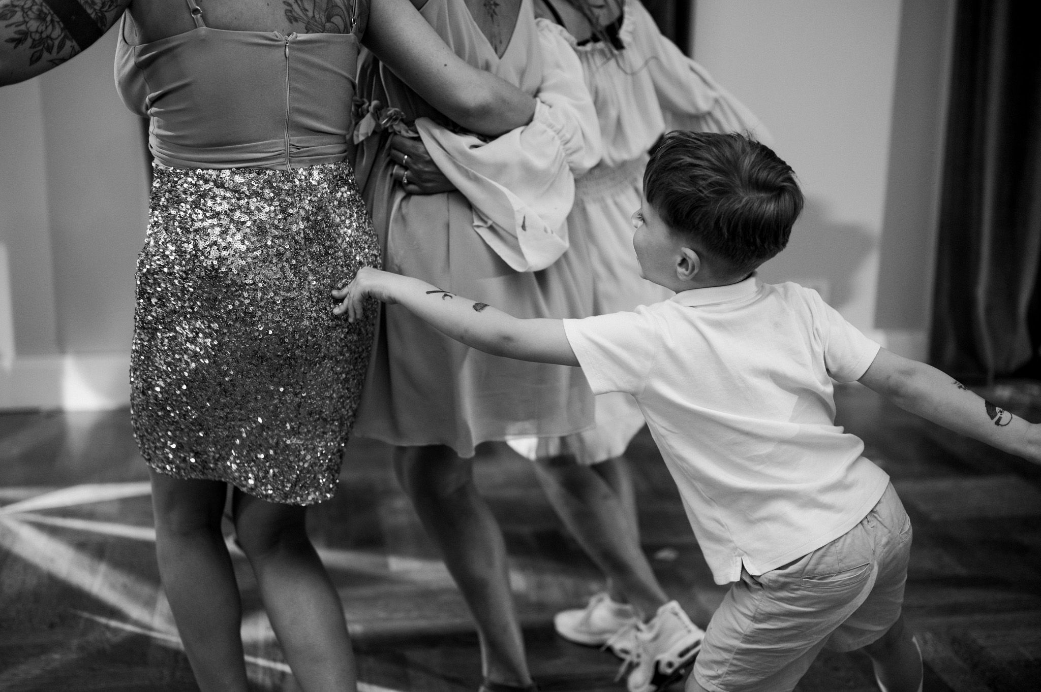Black and white photo of people dancing, with someone in bright white attire energetically moving.