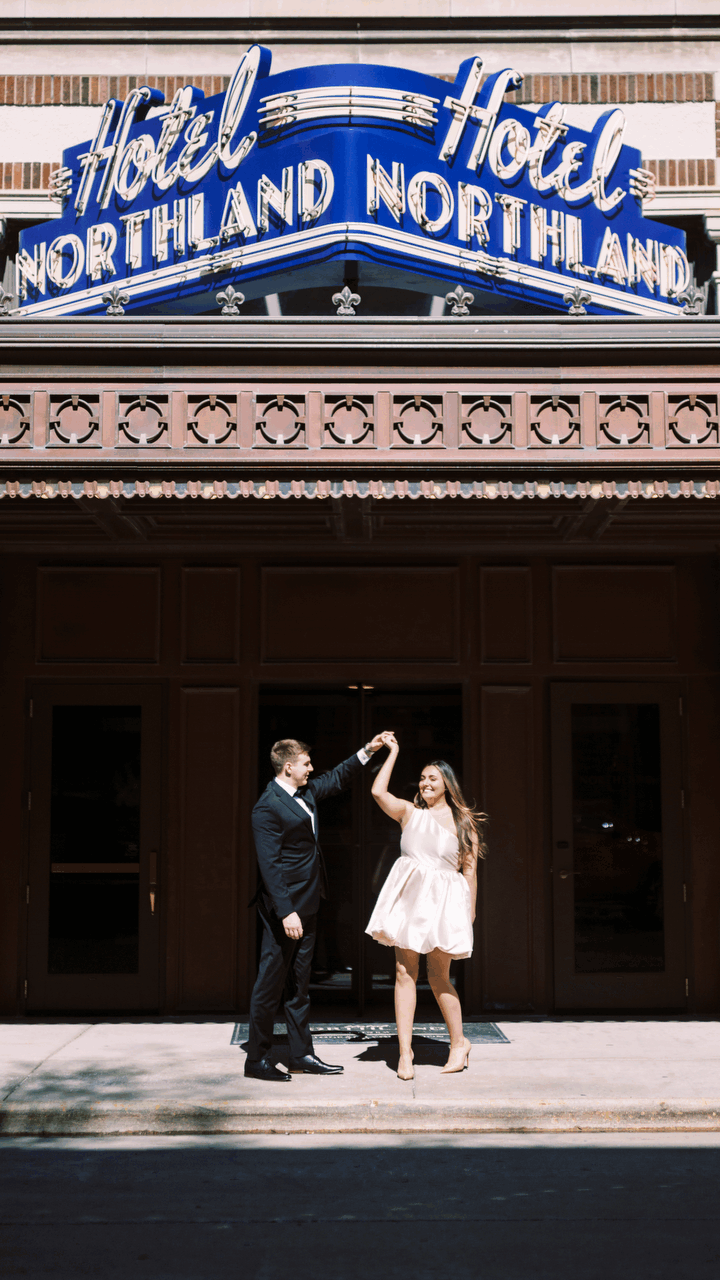 A couple dances beneath the vintage blue neon sign of Hotel Northland, creating a romantic retro scene.