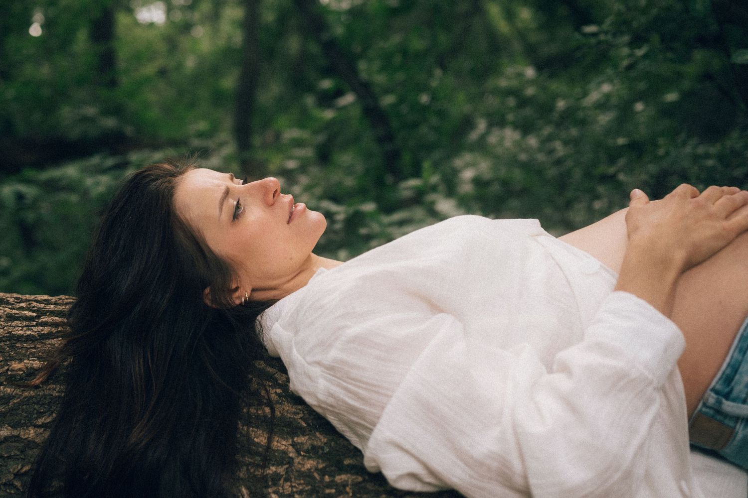 A woman in a white dress lying peacefully on a wooden surface outdoors.
