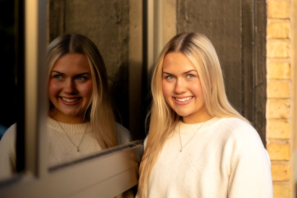 Portrait by a window showing a reflection in warm natural lighting.