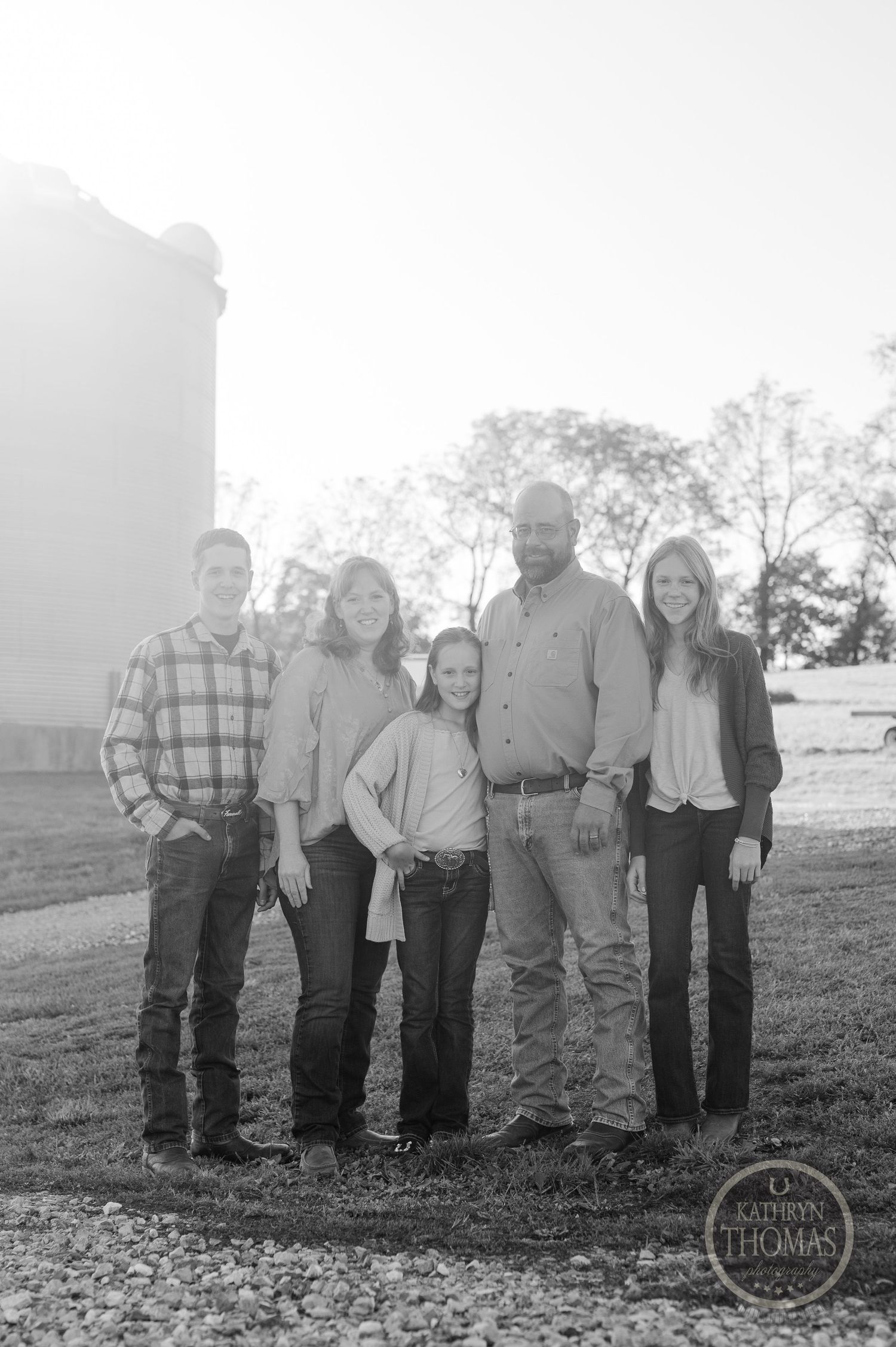 Black and white portrait of family of five standing together outdoors.
