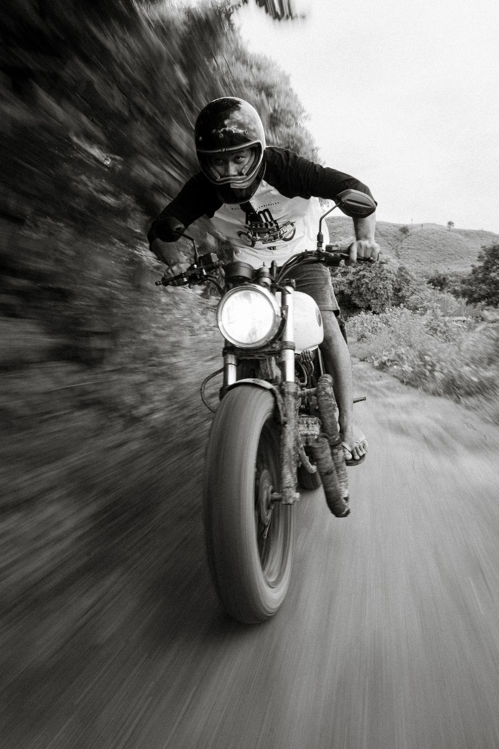 Dynamic black and white photo of motorcycle rider leaning into curve with motion blur.