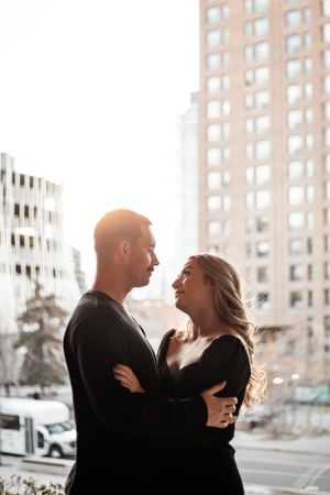couple looking at each other with city building behind