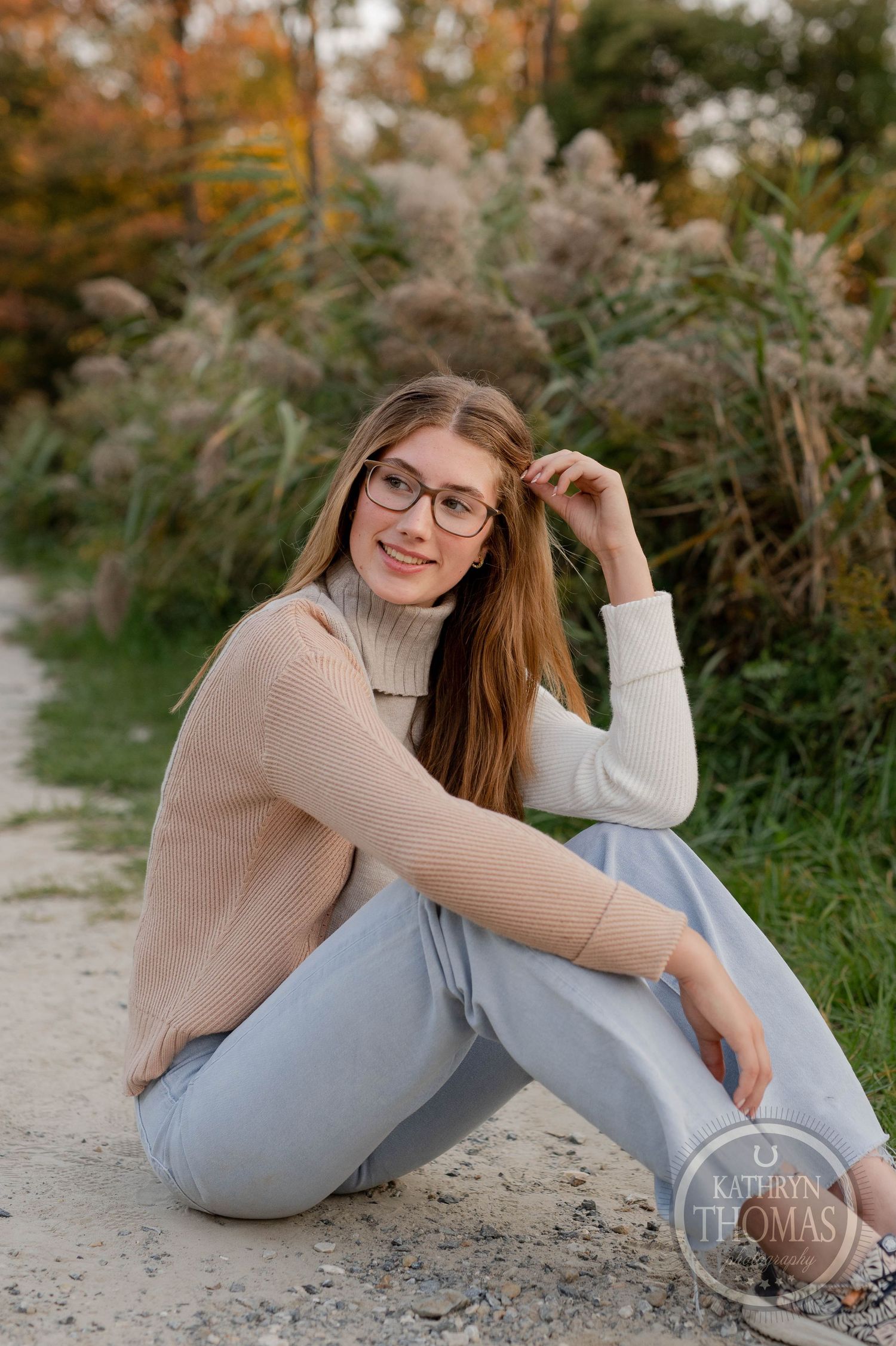 Relaxed outdoor portrait on path with ornamental grasses and natural autumn scenery.