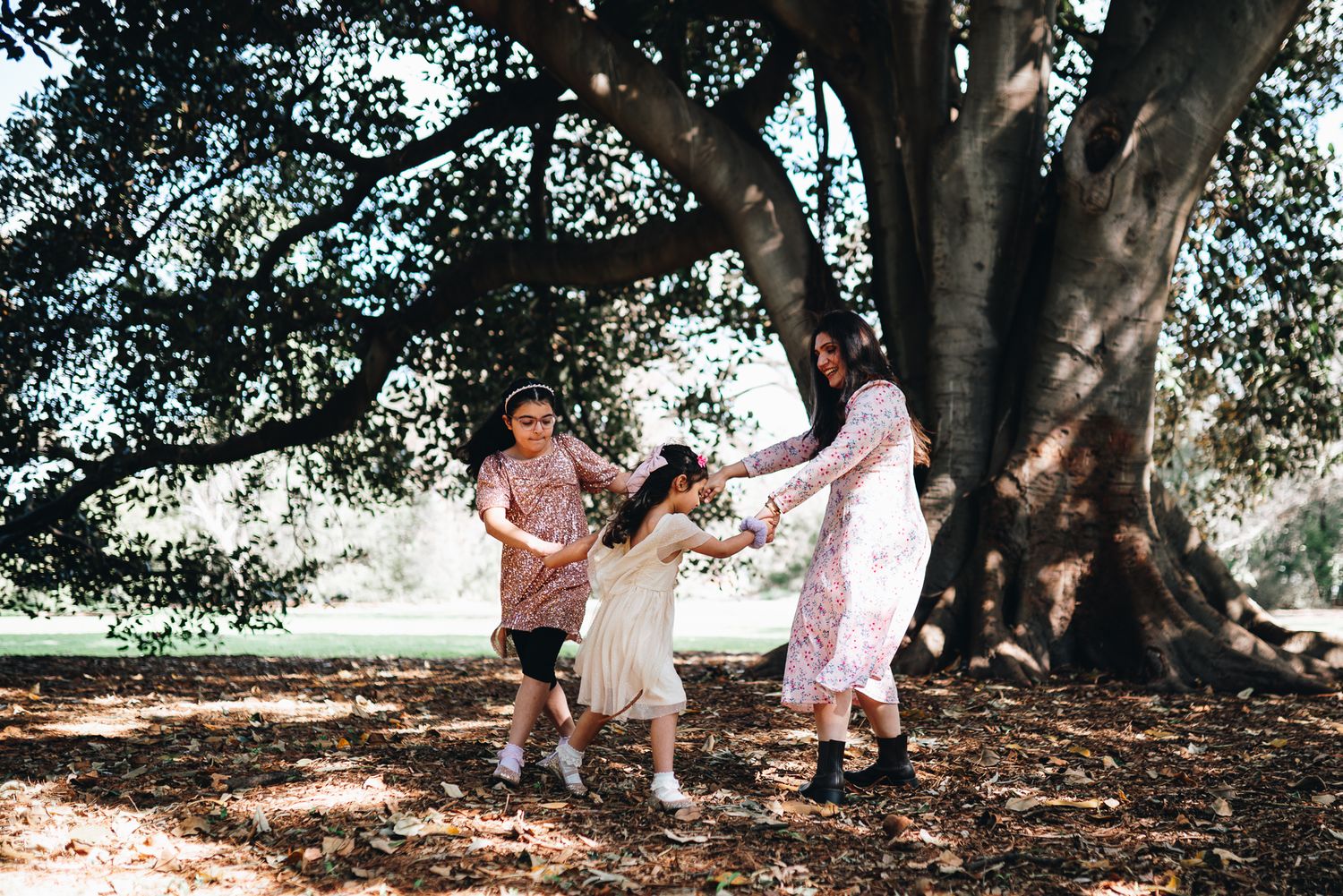Mother and 2 daughters having fun in a family photoshoot in Melbourne's St Kilda Botanical Gardens with lush greeneries as backdrop