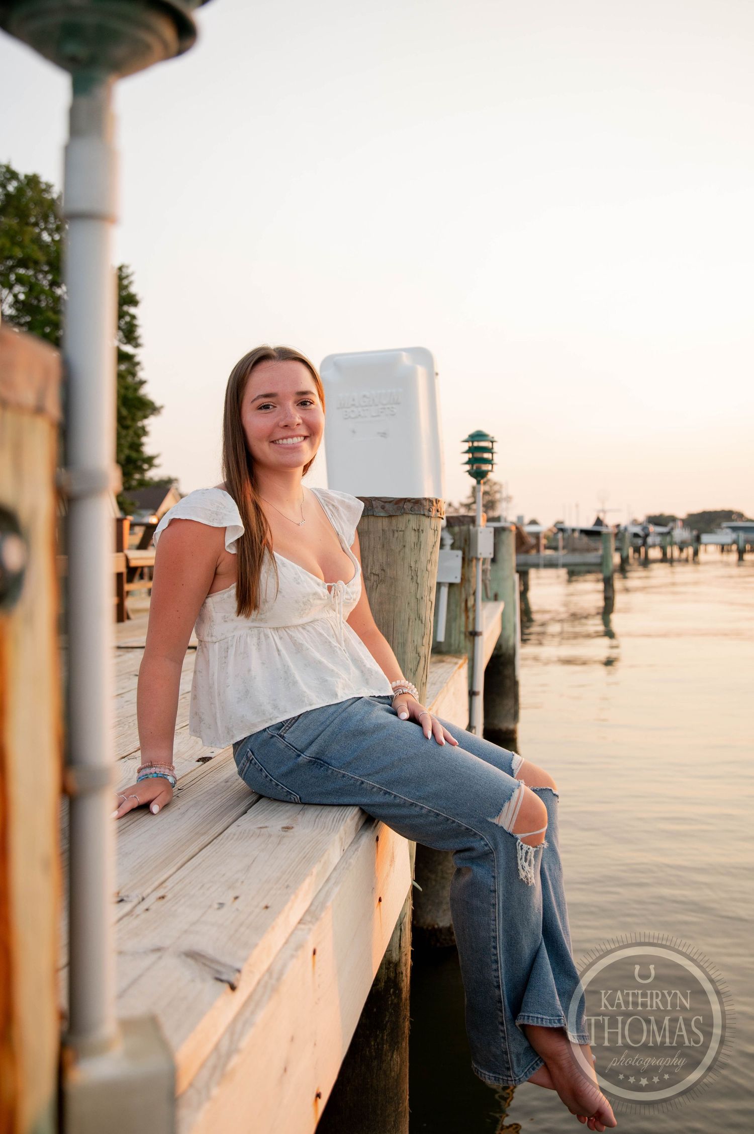 Person relaxing on wooden dock by the water during golden hour.