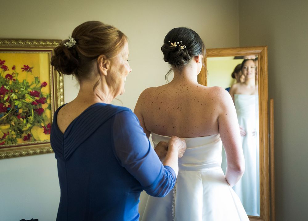 Wedding preparations take place in a warmly lit indoor setting with attendants helping.