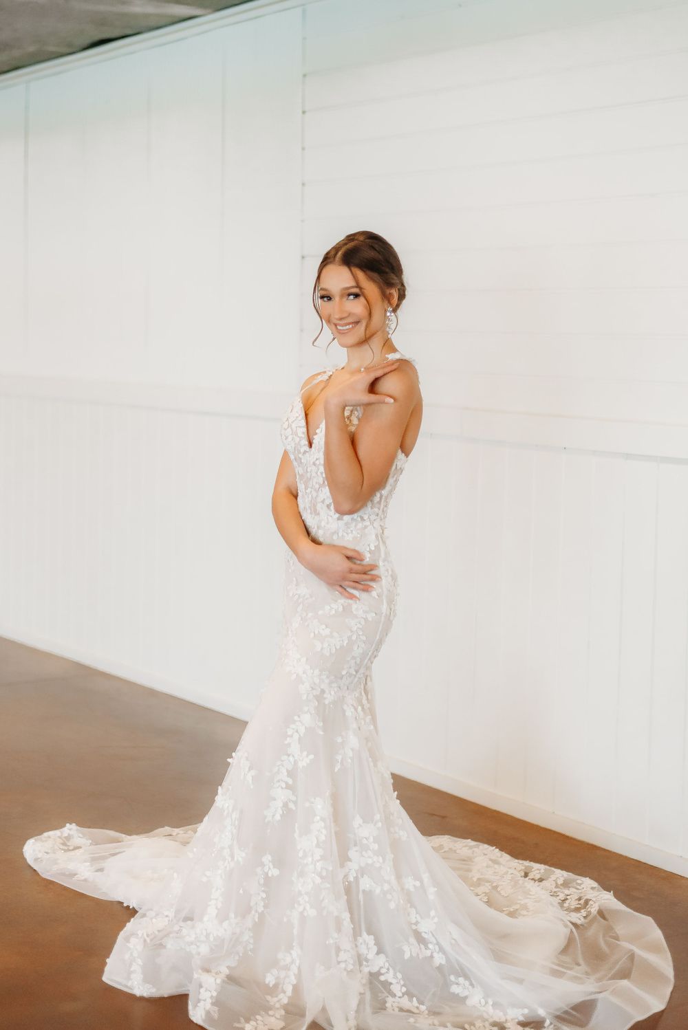 Elegant lace wedding gown with long train and intricate details against white backdrop.