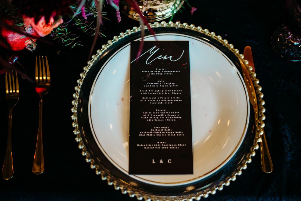 Luxurious place setting with beaded charger plate and black menu card.