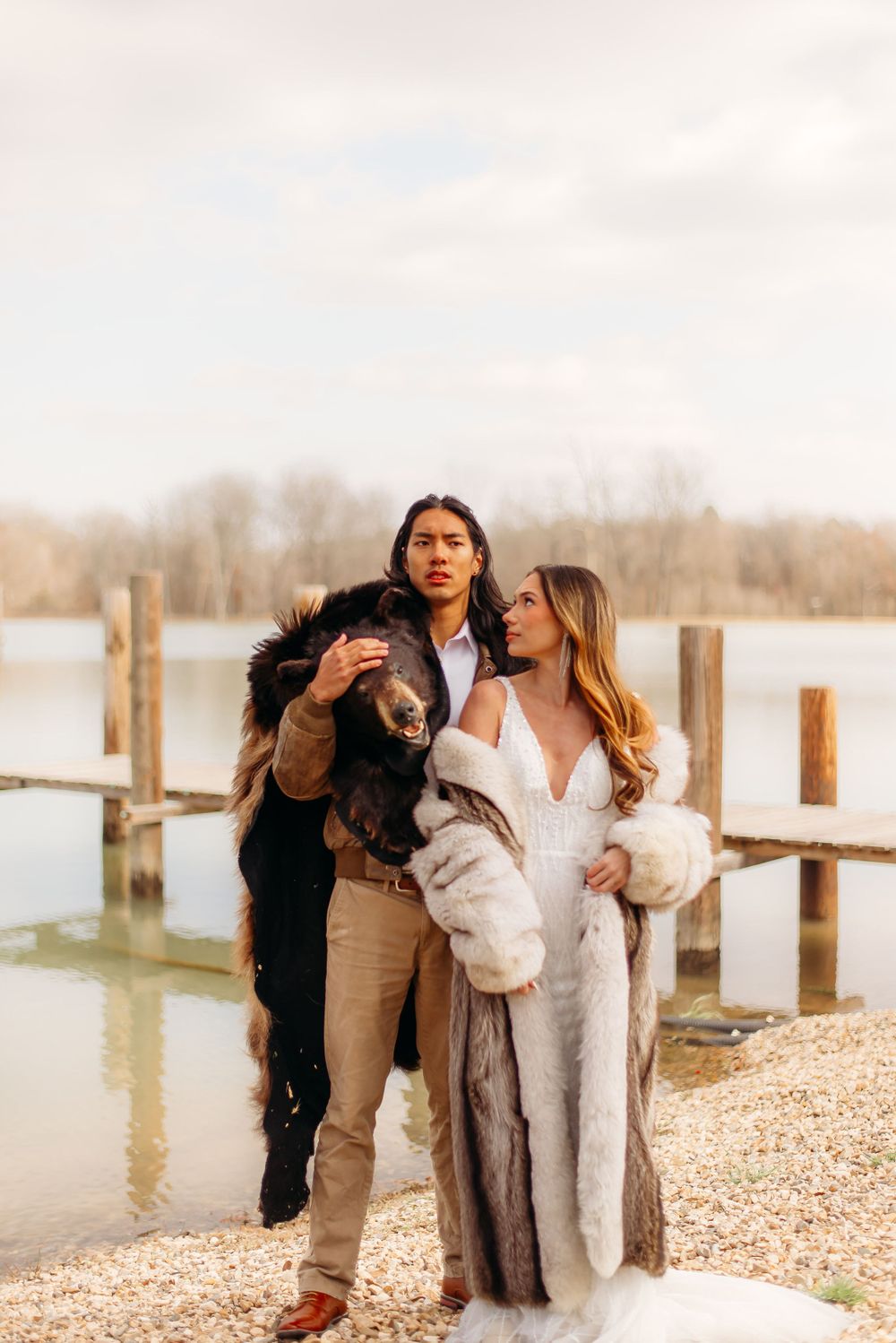 Two people in cozy winter outfits stand together by a waterfront dock.
