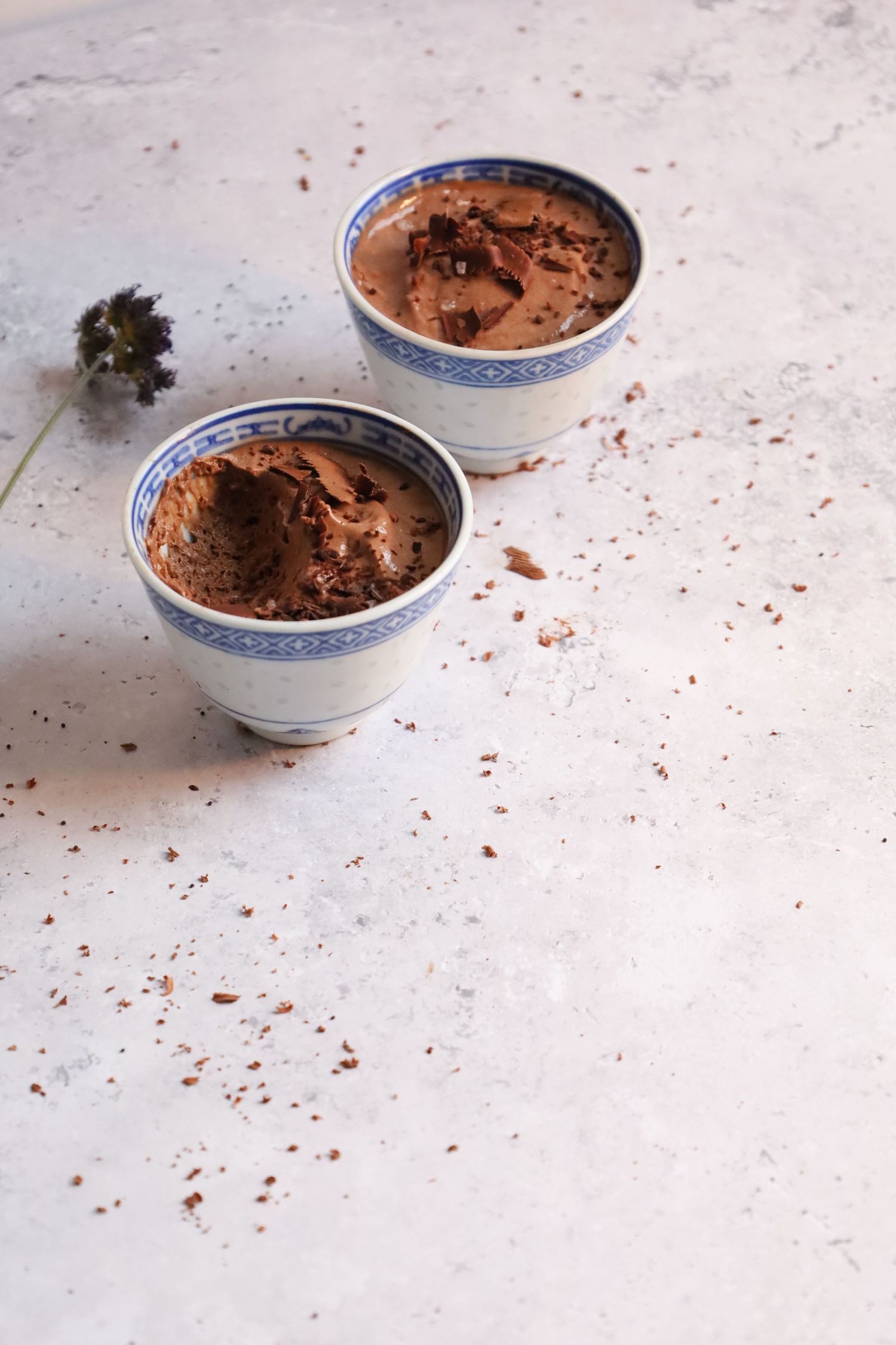 Two bowls of chocolate mousse dessert served on a light marble surface.